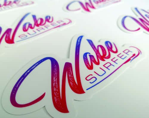 Vibrant, glossy die-cut vinyl stickers with a pink-to-blue gradient “Wake Surfer” design. Perfect for lifestyle branding, water sports gear, or promotional use.