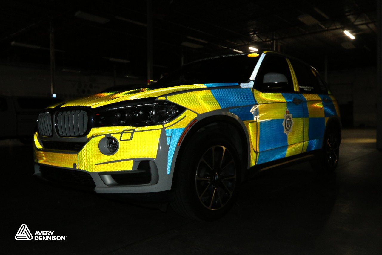 Emergency vehicle wrapped with high-visibility Visiflex Prismatic reflective vinyl graphics shown in a dark indoor setting. 